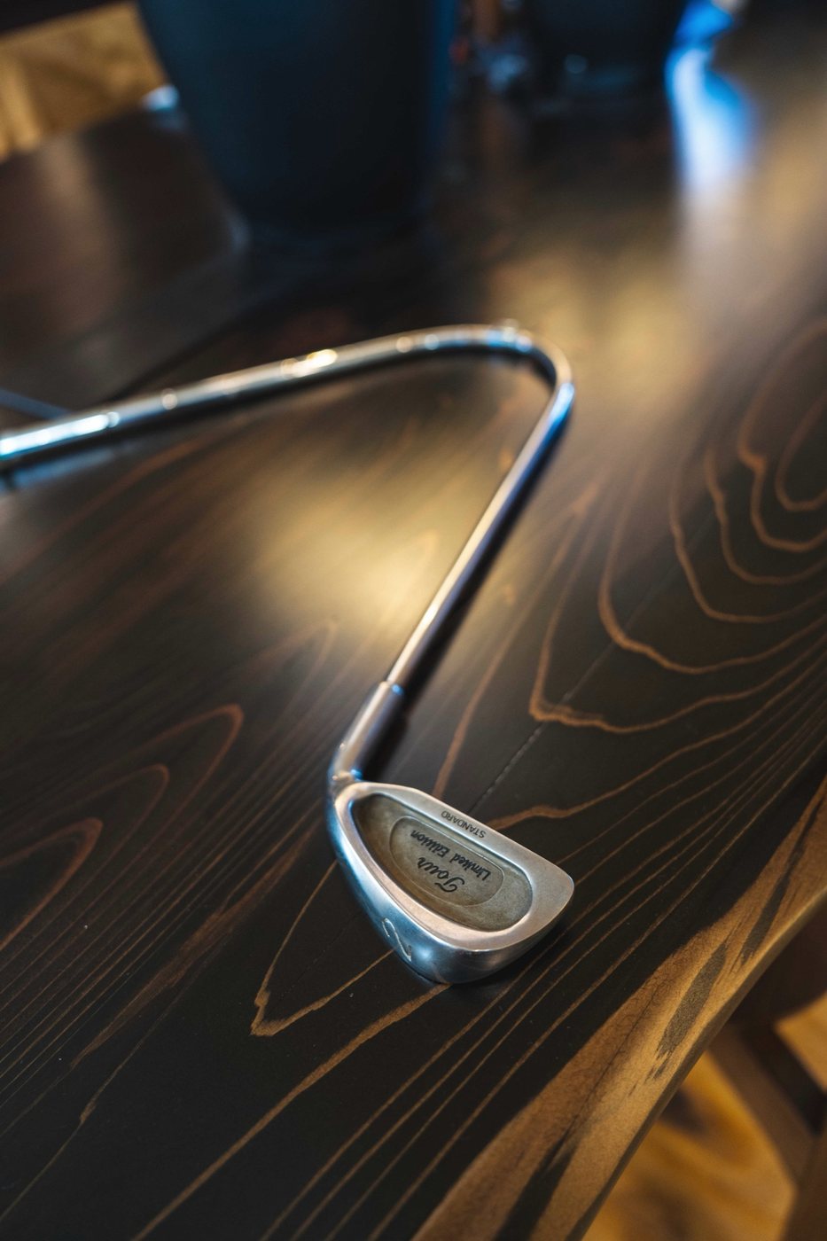 A bent vintage iron lying on a dark wood table, seen from above